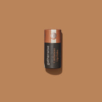 A single Gatherwise Cardamom Lip Balm tube centered on a warm tan background.