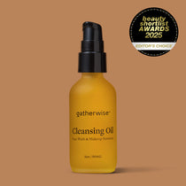 A bottle of Gatherwise Cleansing Oil with a black pump dispenser and amber-yellow bottle, set against a solid warm brown background. A Beauty Shortlist Awards 2025 badge is displayed in the upper right corner.