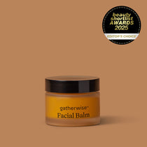 A jar of Gatherwise Facial Balm with a black lid and amber-brown body, set against a solid warm brown background with a Beauty Shortlist Awards 2025 badge is displayed in the upper right corner.