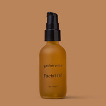 A frosted glass bottle of Gatherwise Facial Oil with a black pump dispenser, centered against a solid warm brown background.